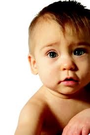 Close-up of a baby with fair skin, light brown hair, and blue eyes looking directly at the camera against a white background.