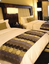 Hotel room with two double beds, headboards, lamps, and patterned bed runners.