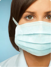 Healthcare worker wearing a surgical mask, looking directly at the viewer. Focus on protection and safety.