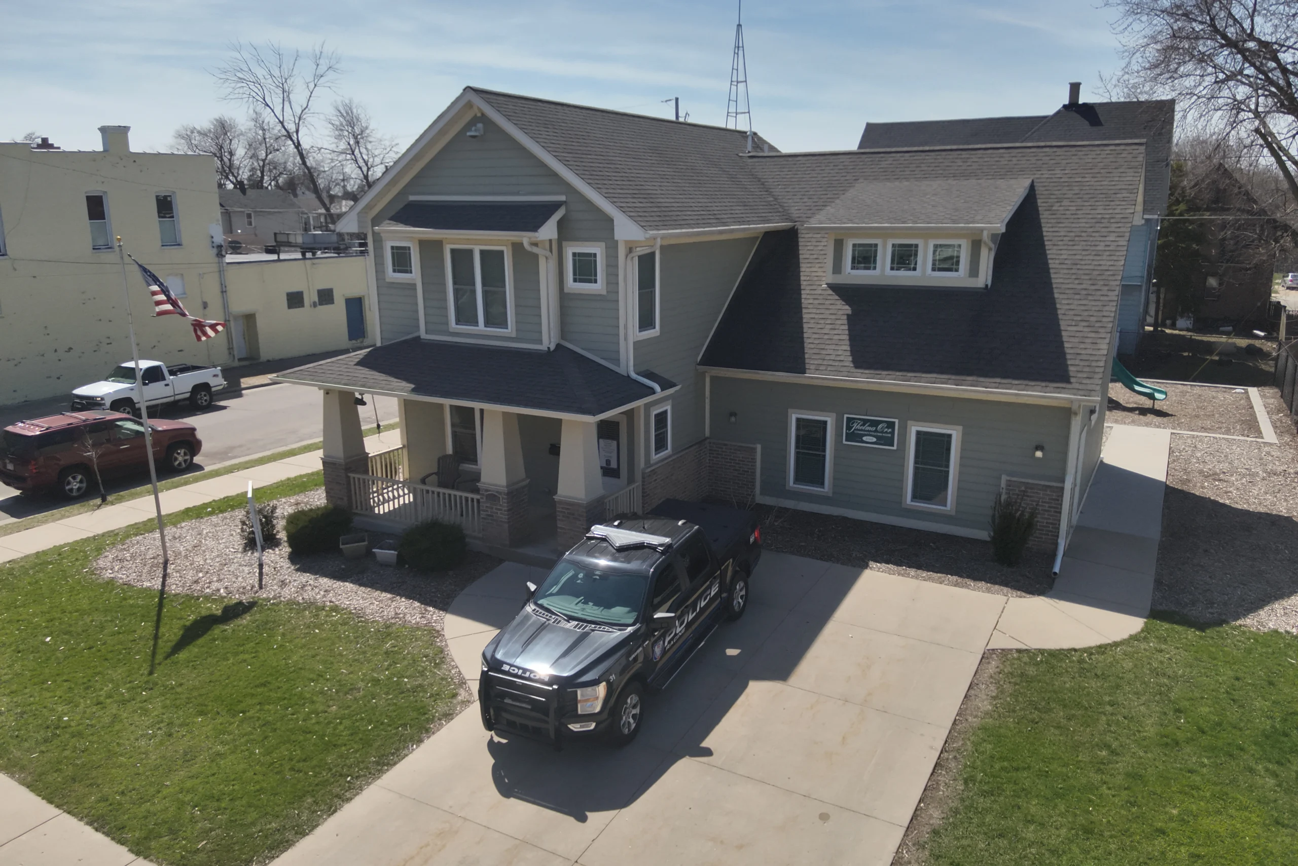 Two-story gray house with black truck parked in driveway on a sunny day.