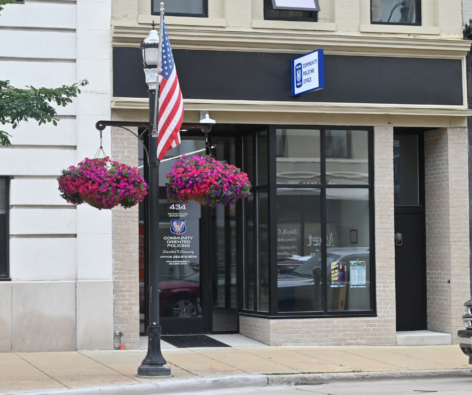 Exterior view of a building with an American flag and hanging flower baskets. Sign reads 'Property Showing Only'.