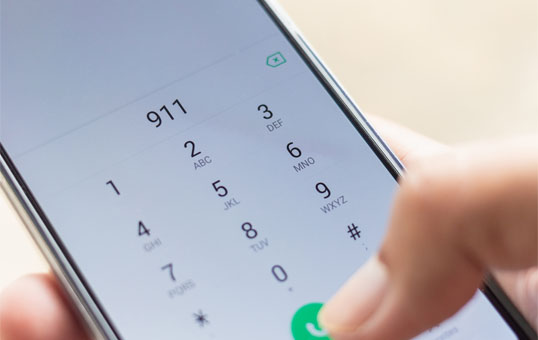 Hand dialing 911 on a smartphone. Emergency call being placed.