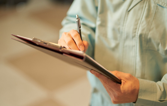 Person holding clipboard and writing with pen. Focus on hands and clipboard.