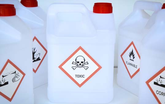 Plastic containers with hazard symbols: toxic, corrosive, flammable, and environmental hazard.