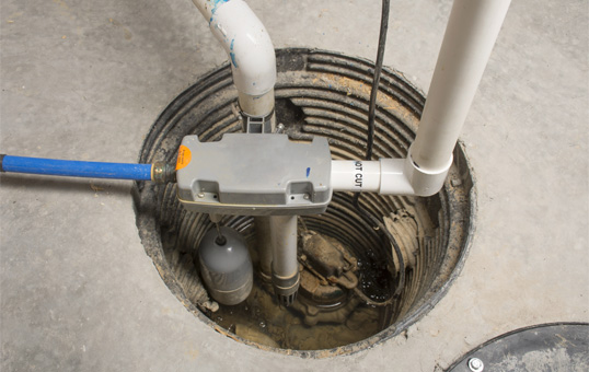 Sump pump installed in a concrete basement floor, with pipes and float visible.