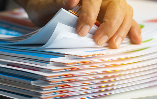 Hand flipping through a stack of colorful papers, possibly reviewing documents or organizing files.