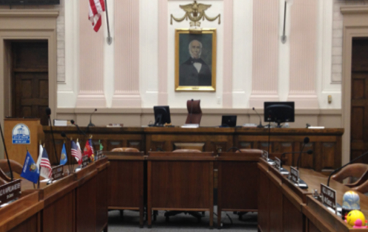Interior view of a government chamber with flags, portraits, and seating arrangements.