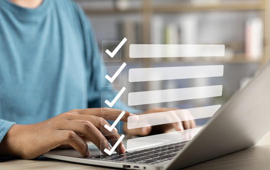 Person completing an online form on a laptop, with checkmarks indicating completed fields.