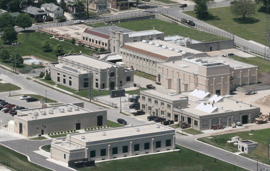 Aerial view of a complex of beige brick buildings with flat roofs and manicured lawns.