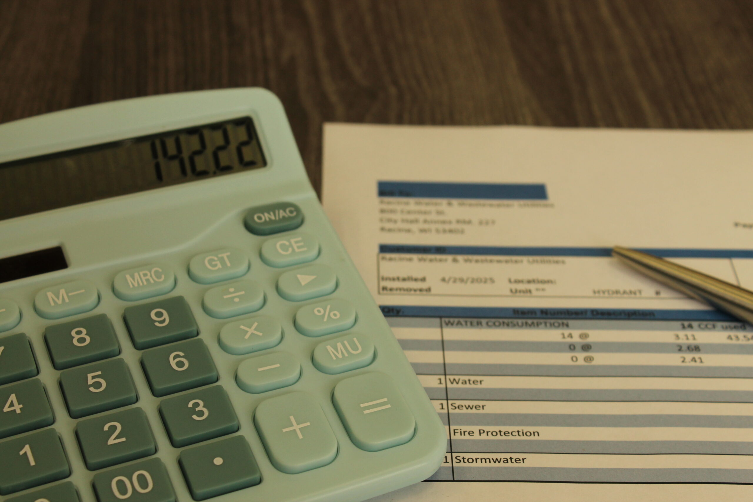 Person calculating figures with a calculator and writing in a binder. Focus on hands and calculator.