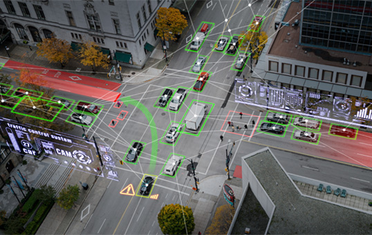 Aerial view of a city intersection with cars highlighted by green boxes, representing smart city technology.