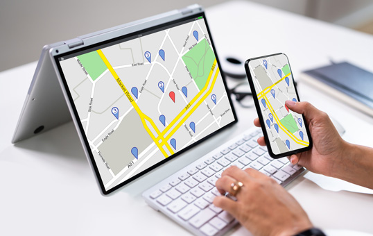 Person using map application on laptop and phone. Location markers displayed on both devices.