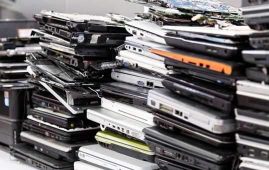 Pile of discarded laptops and computer parts, representing e-waste and the need for responsible recycling.
