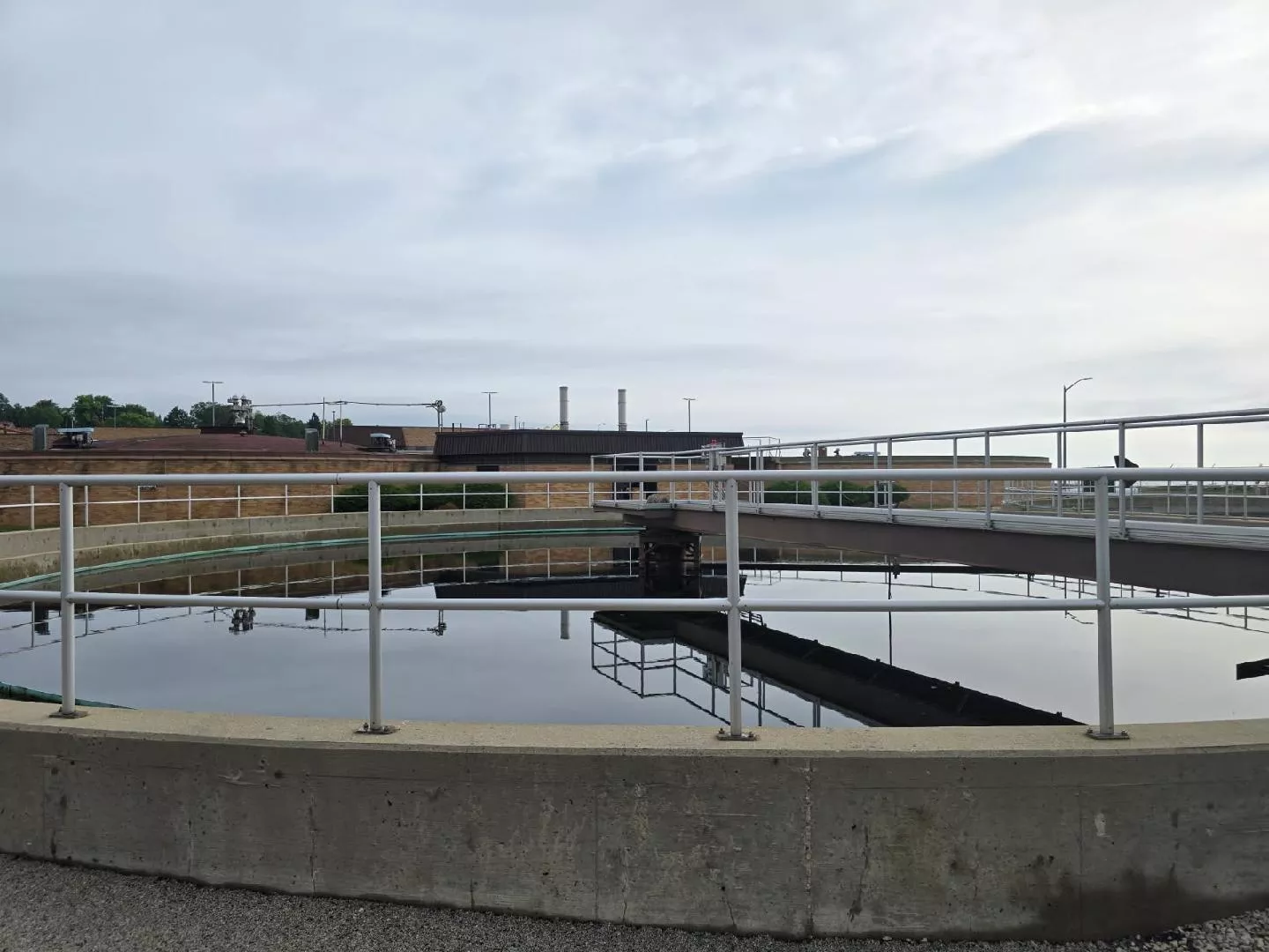Circular water treatment tank with bridge and handrails, part of a water purification facility.
