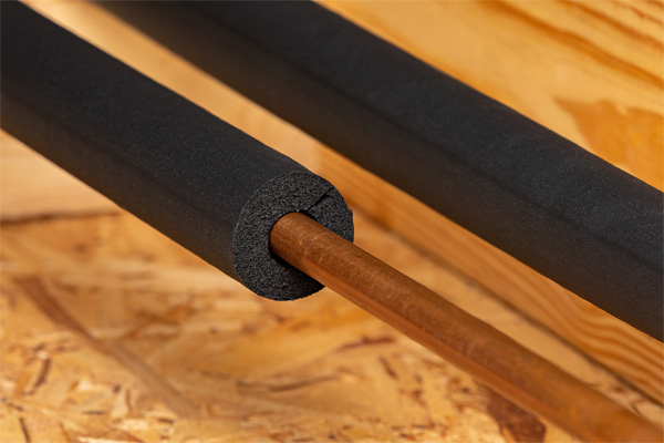 Copper pipe insulated with black foam tubing to prevent heat loss and condensation.