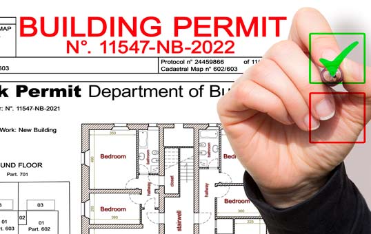 Building permit document with a hand marking a green checkmark indicating approval.