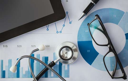 Stethoscope, glasses, tablet, and pen on medical charts. Healthcare data analysis concept.