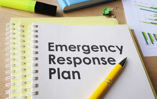 Emergency Response Plan document on a desk with pen, highlighter, and charts. Business planning concept.