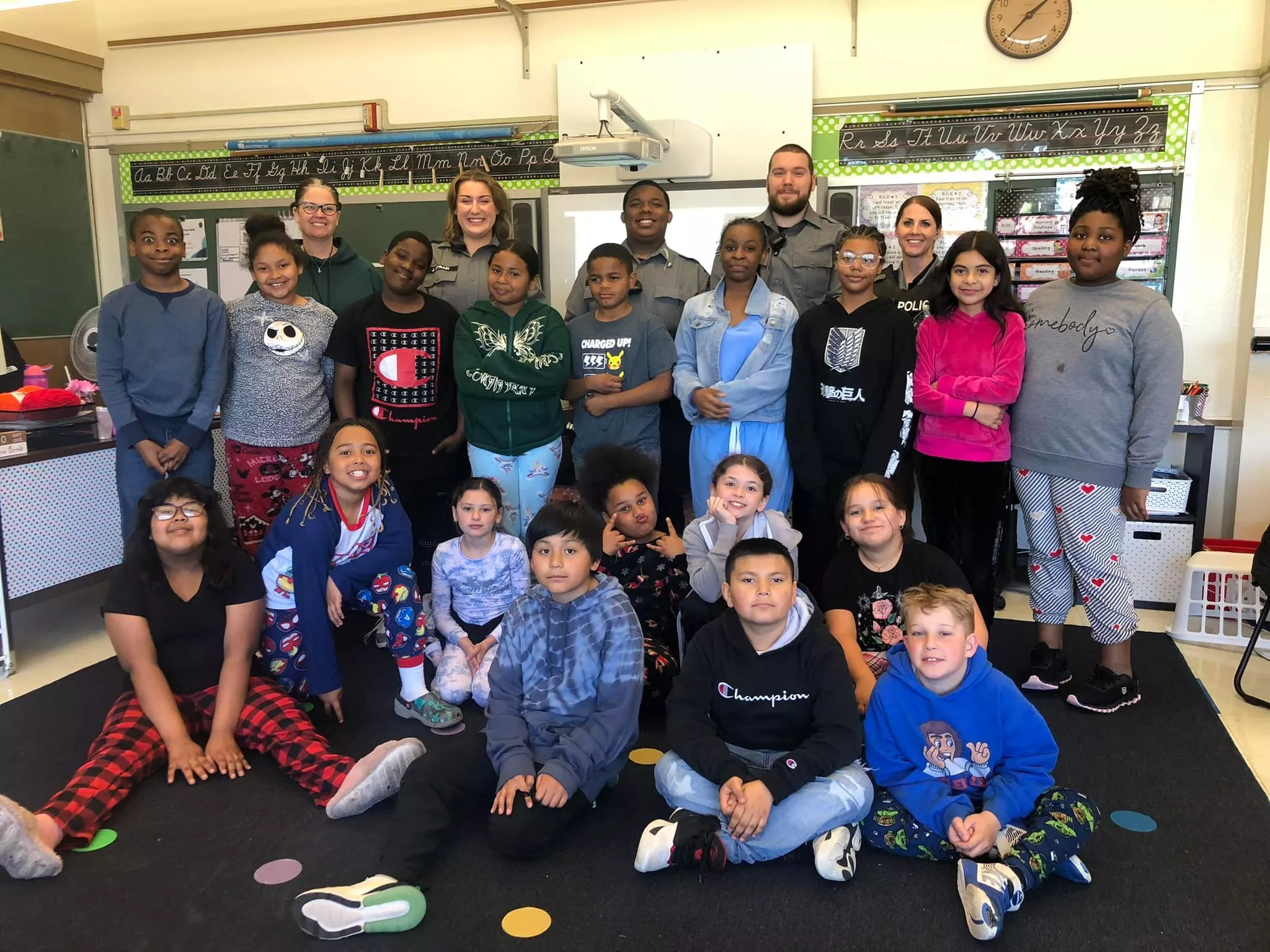 Group photo of elementary students with police officers in a classroom setting.