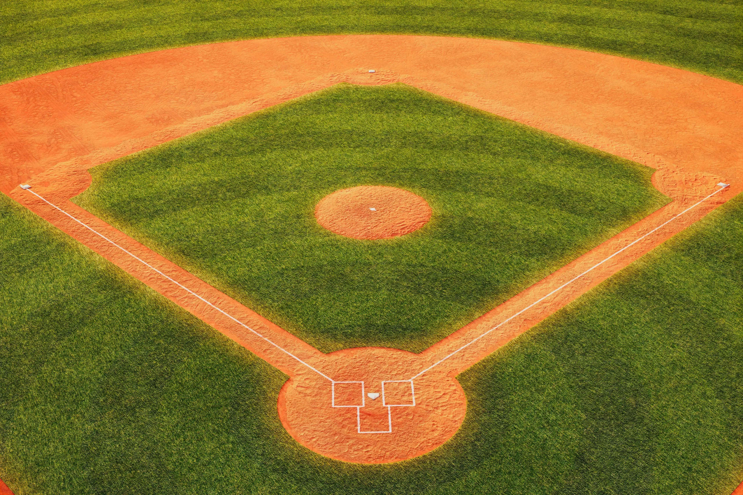 Aerial view of a baseball infield with green grass and orange dirt base paths and pitcher's mound.