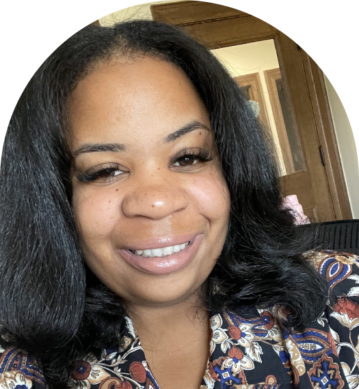 Headshot of a smiling Black woman with long dark hair wearing a patterned top.
