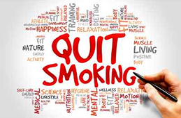 Quit Smoking text in red surrounded by health and wellness related words. Hand holding pen.