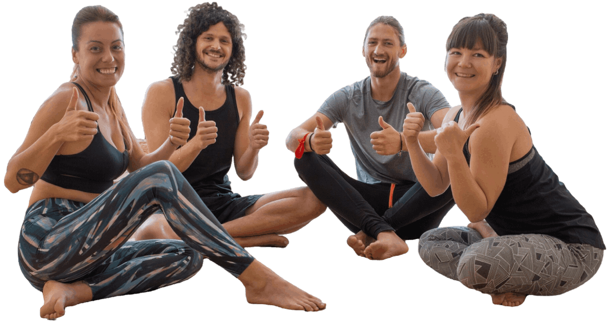Group of four smiling people seated cross-legged giving thumbs up, promoting wellness or positive feedback.