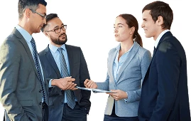 Four businesspeople in suits discussing a document, collaborating on a project in a professional setting.