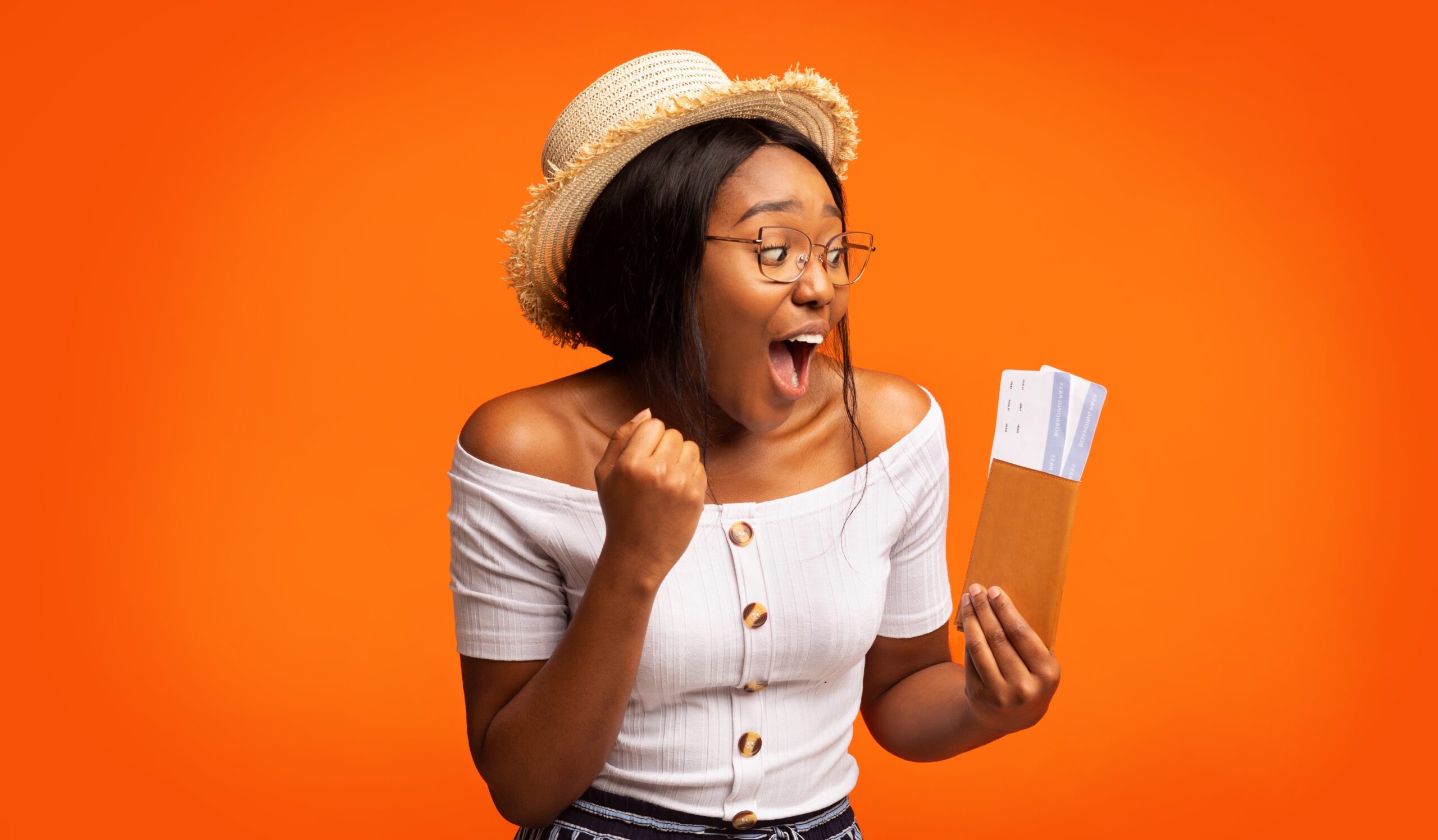 Excited,Black,Woman,Holding,Tickets,And,Passport,Standing,,Orange,Background